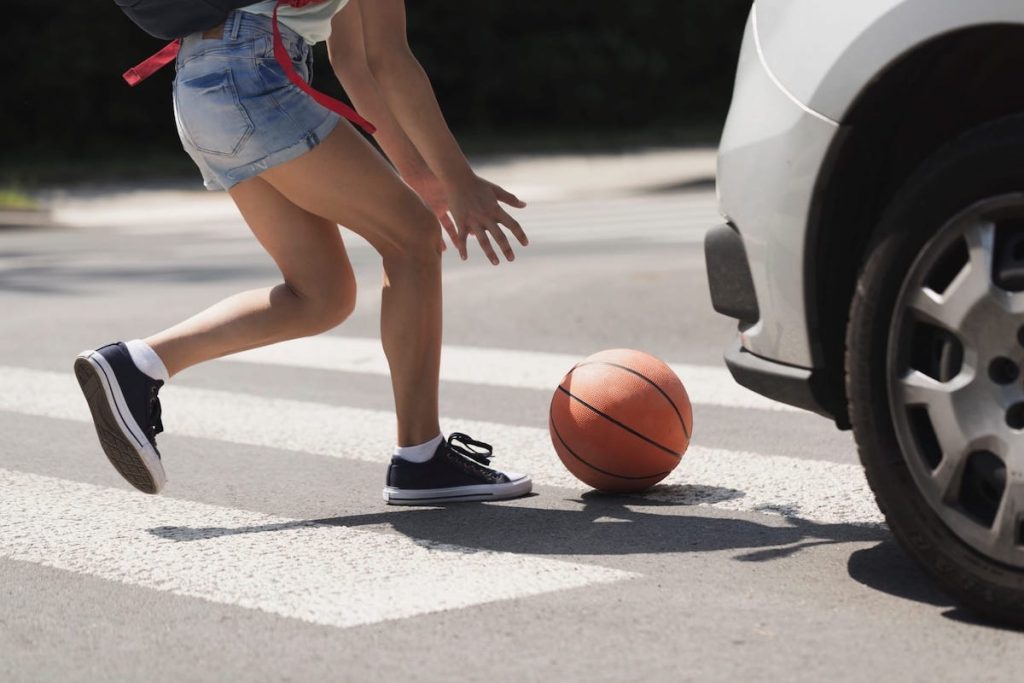 Girl Chasing A Ball On The Road With Cars