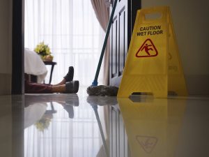 Legs Of A Fallen Woman Next To A Slippery Warning Sign