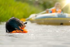 Child With An Orange Vest In Water