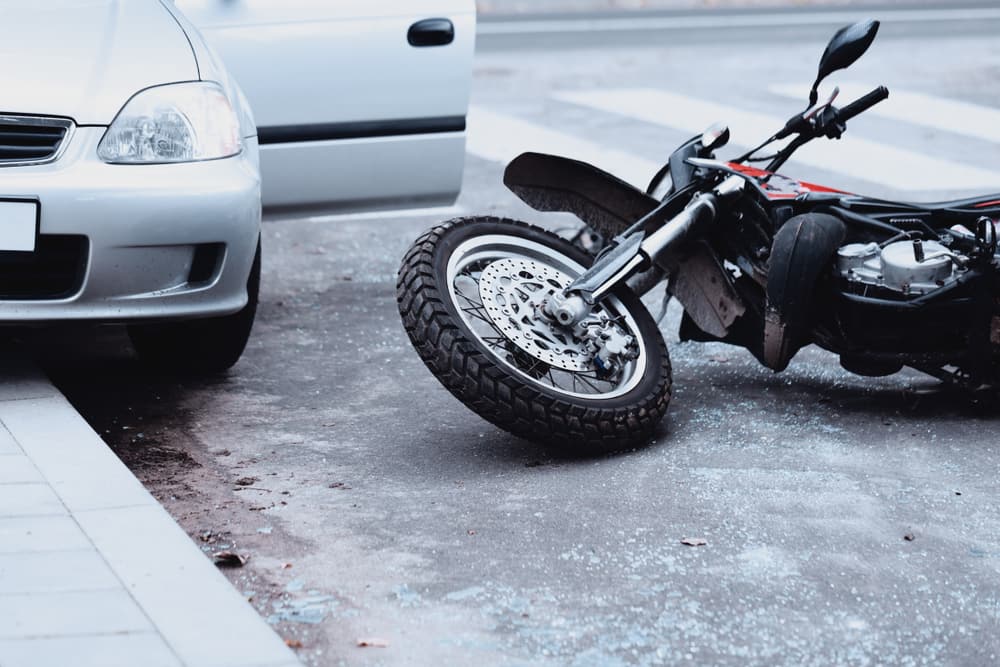 Red Motorcycle On Fallen On Its Side Next To A White Car