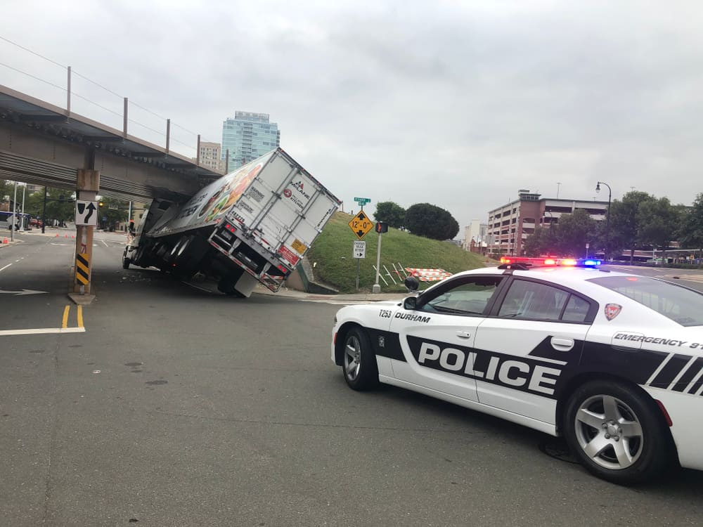 Police Car Behind A Truck That Has Stuck Under A Bridge