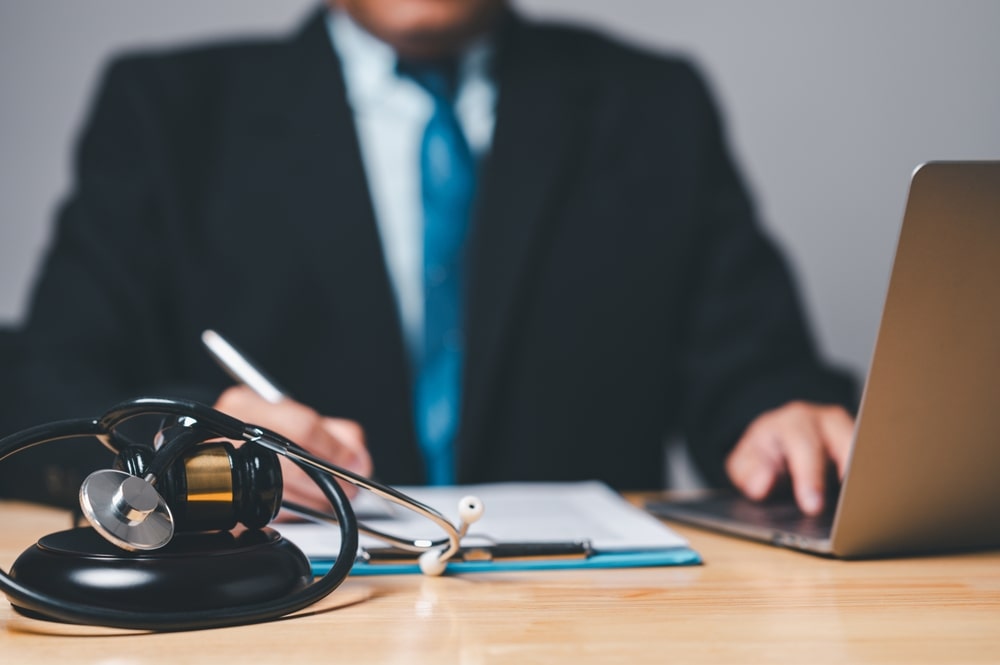 Lawyer Filling Out Documents With A Stethoscope In Front Of Him