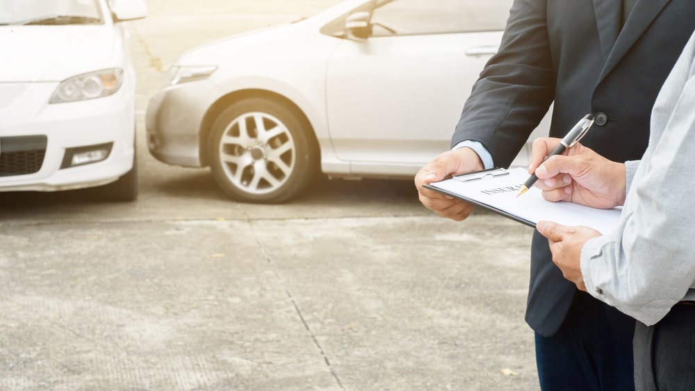 Man Signing Some Documents Next To A Car Accident Scene