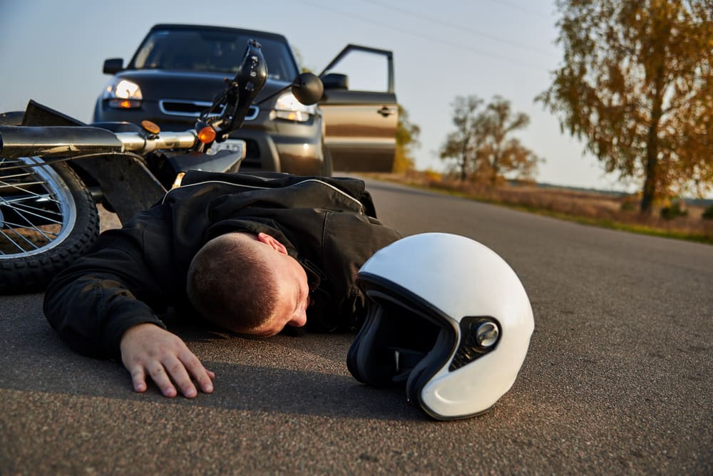 Man Laying On The Road Next To A Motorcycle